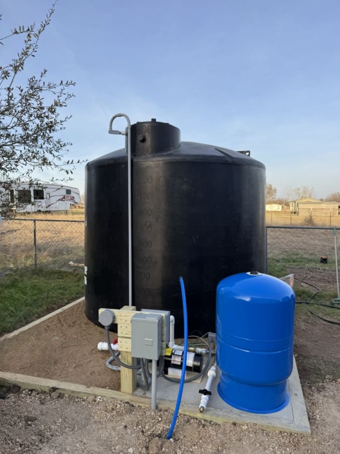 Complete water storage system with a 2,500-gallon tank, booster pump, pressure tank and control post on a crushed granite pad