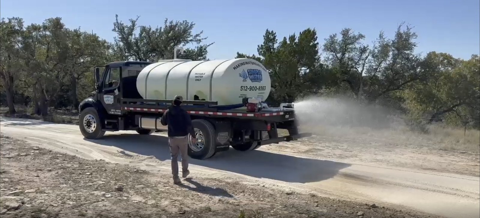 Simple Water Solutions water truck applying dust control on a caliche road in Central Texas